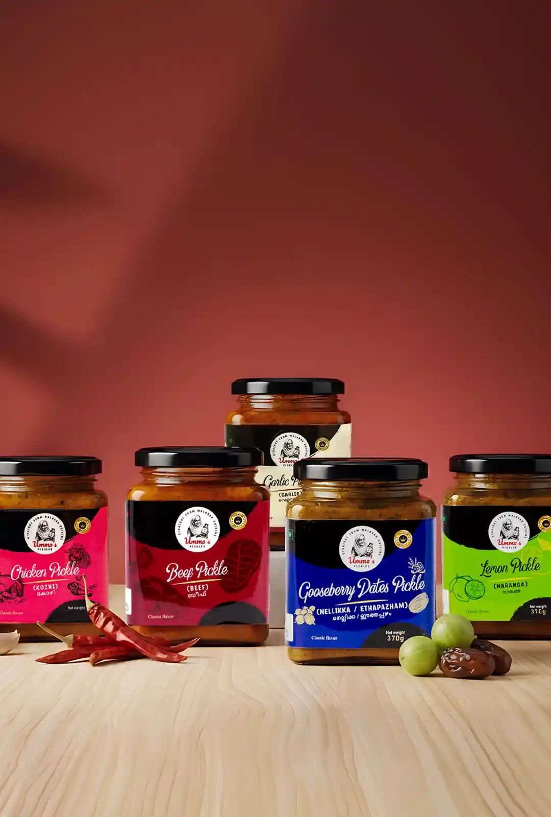 Jars of different flavors of pickles on a wooden surface with a red background