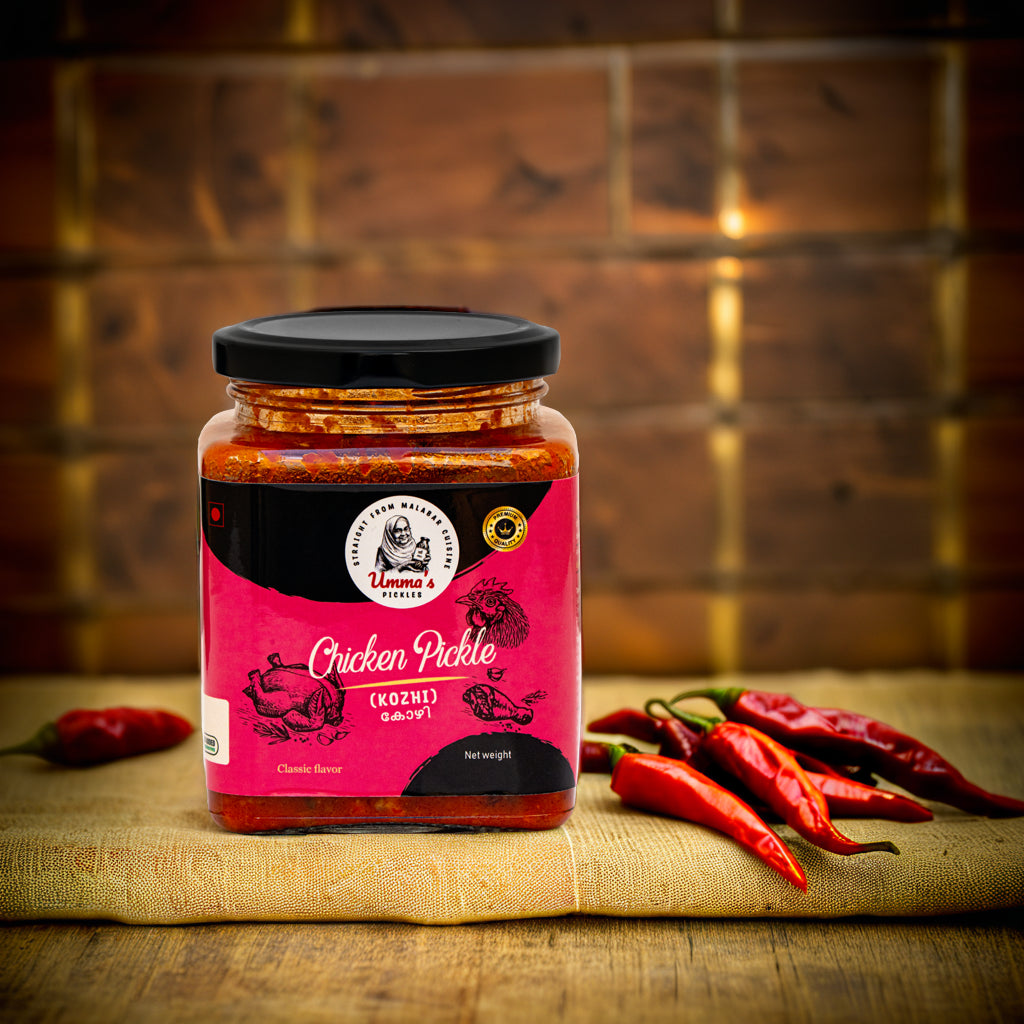 Jar of chicken pickle with a pink label on a wooden surface with red peppers.